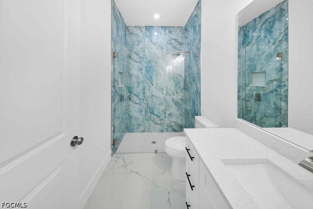 2416/2418 Joe Avenue S, Lehigh Acres, FL 33973 Full bathroom featuring a frameless glass shower enclosure with blue-toned marbled wall tile, a built-in shower niche, a white vanity with an integrated sink, and white floor tiling