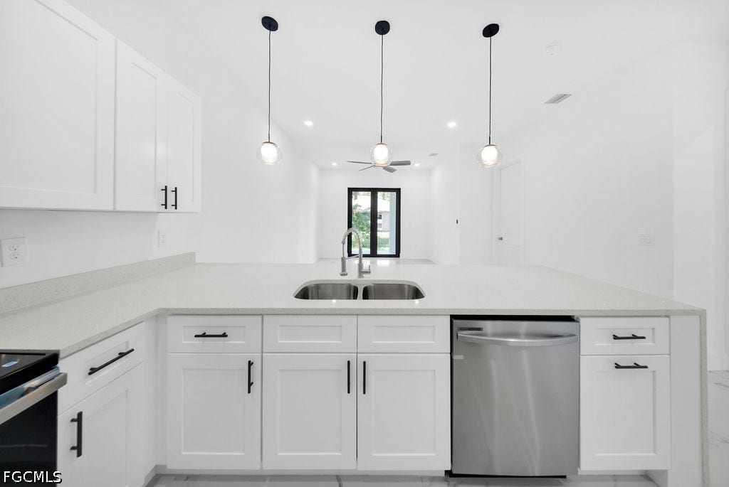 2416/2418 Joe Avenue S, Lehigh Acres, FL 33973 Kitchen featuring white shaker cabinetry, light-toned countertops, a double basin stainless steel sink, a stainless steel dishwasher, and pendant lighting