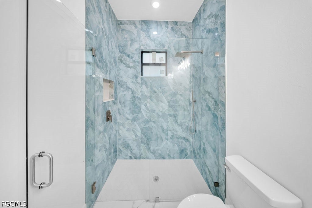 2416/2418 Joe Avenue S, Lehigh Acres, FL 33973 Glass-enclosed shower with blue-patterned wall tiling and integrated niche