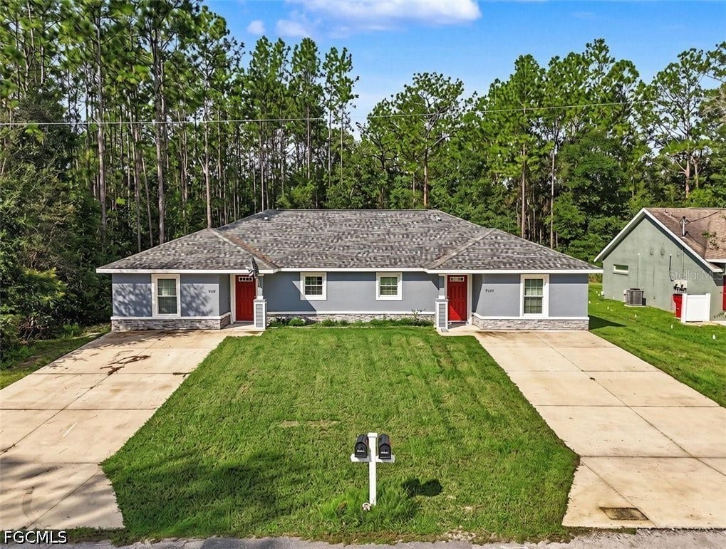 9342/9344 N Peachtree Way, Citrus Springs, FL 34434 Duplex property featuring a grey exterior with stone accenting, separate concrete driveways, and a shingle roof