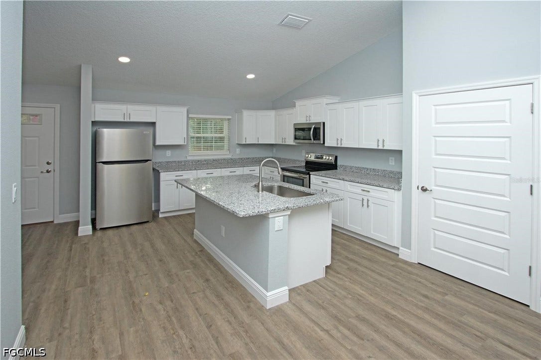 9342/9344 N Peachtree Way, Citrus Springs, FL 34434 Kitchen featuring white cabinetry, a center island with a sink, stainless steel appliances, and wood-finish flooring
