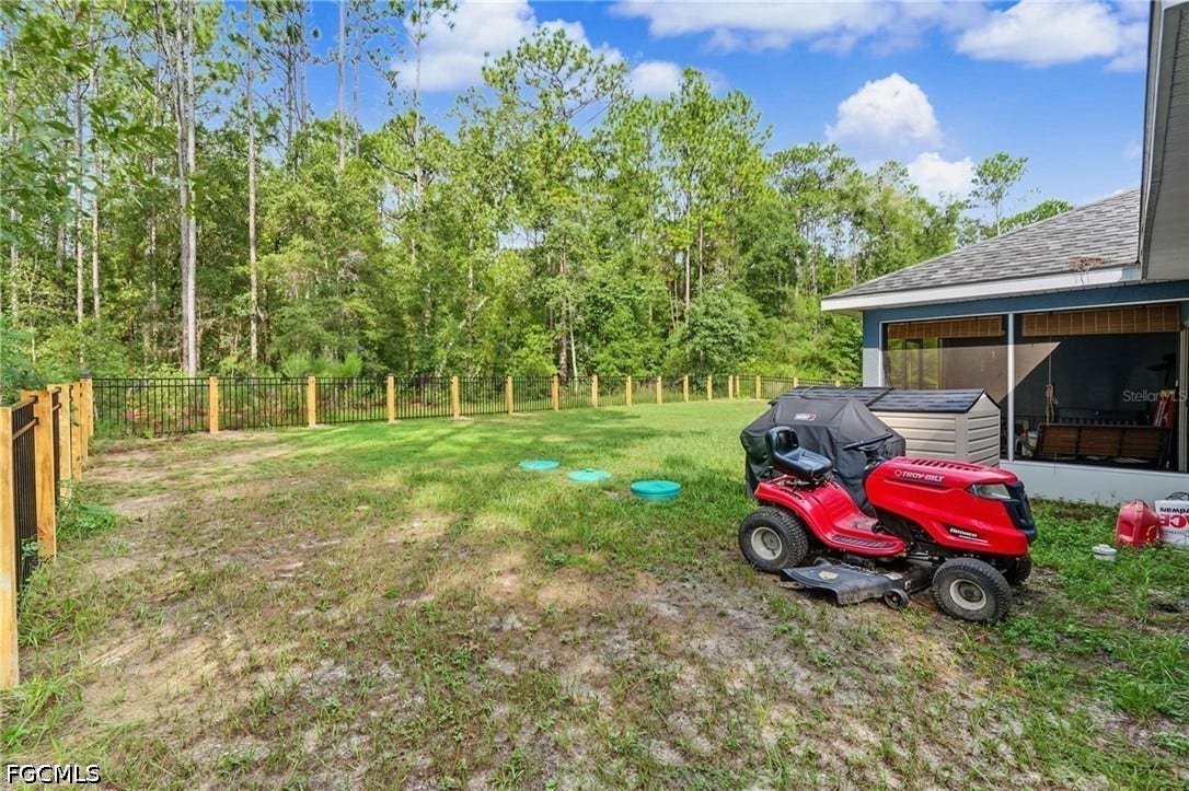 9342/9344 N Peachtree Way, Citrus Springs, FL 34434 Screened porch, fenced perimeter, and natural tree-lined backdrop