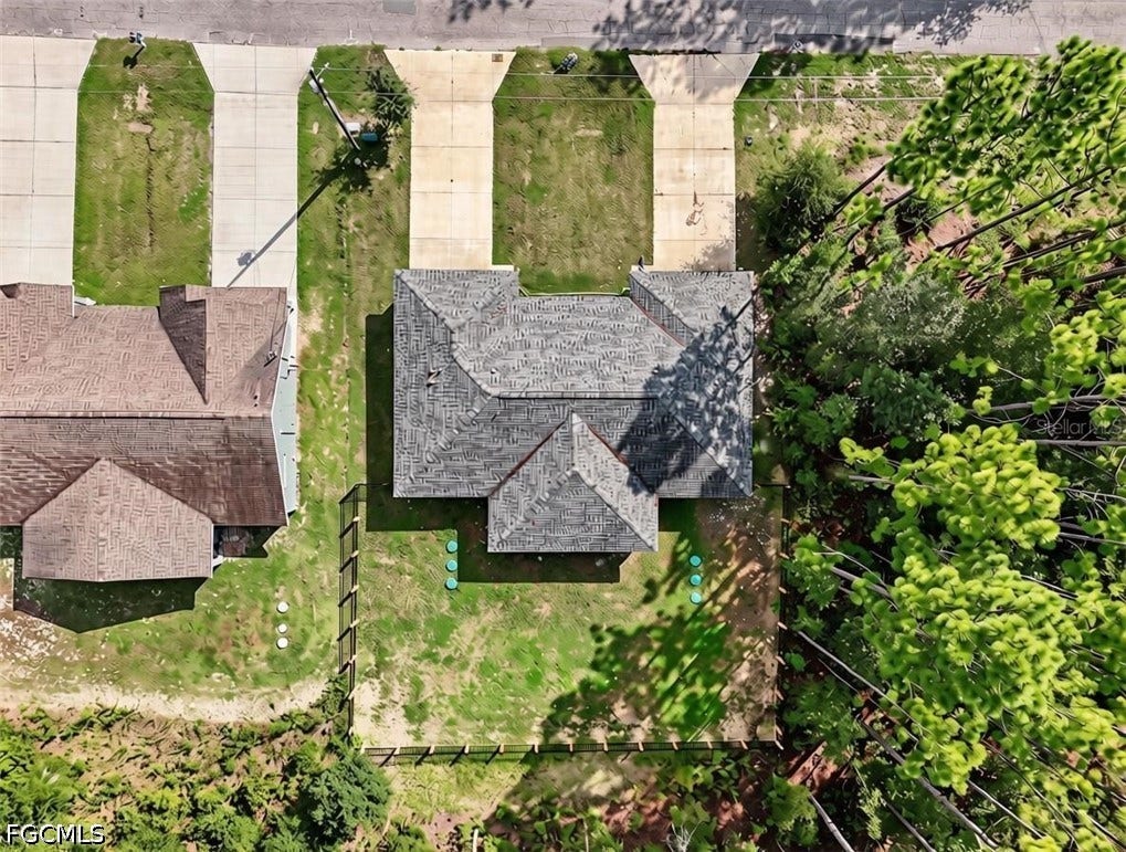 9342/9344 N Peachtree Way, Citrus Springs, FL 34434 Gable roof structure with shingle roofing, expansive green lawn, concrete driveway, and established perimeter fencing
