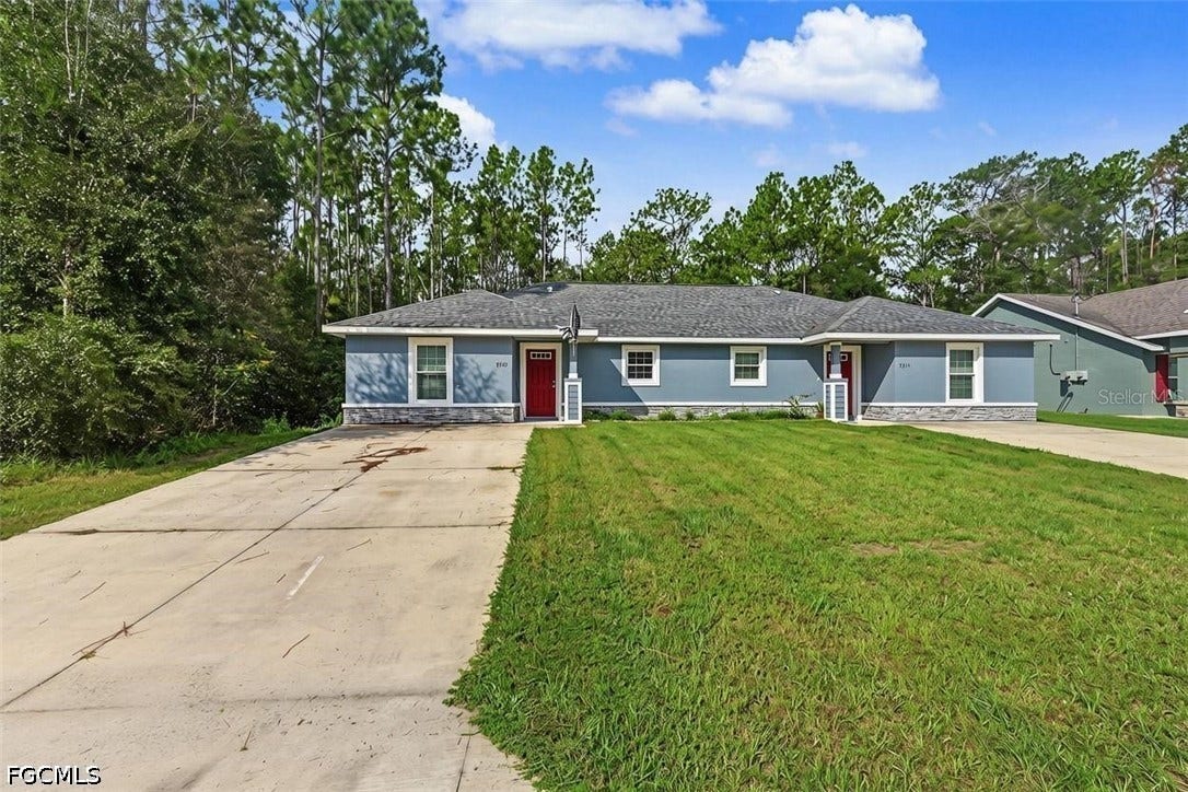 9342/9344 N Peachtree Way, Citrus Springs, FL 34434 Duplex exterior with blue siding, stone veneer accents, individual red entry doors, and a shingled roof