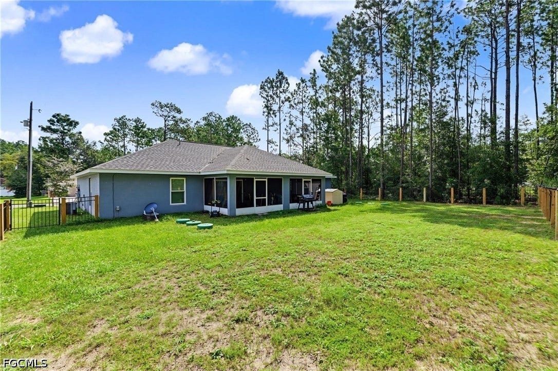 9342/9344 N Peachtree Way, Citrus Springs, FL 34434 Expansive backyard featuring a screened porch, partial wood fencing, partial black metal fencing, and mature trees along the property line
