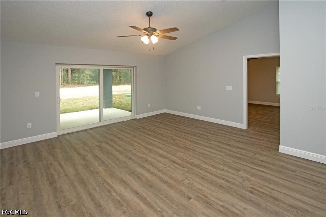 9342/9344 N Peachtree Way, Citrus Springs, FL 34434 Vaulted ceiling living space with wood-finish flooring, sliding glass door access to a patio, and a ceiling fan