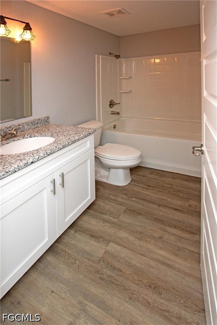 9342/9344 N Peachtree Way, Citrus Springs, FL 34434 Bathroom featuring a white vanity with slab cabinet doors, speckled countertop, an undermount sink, a vanity mirror, and a full bathtub with shower