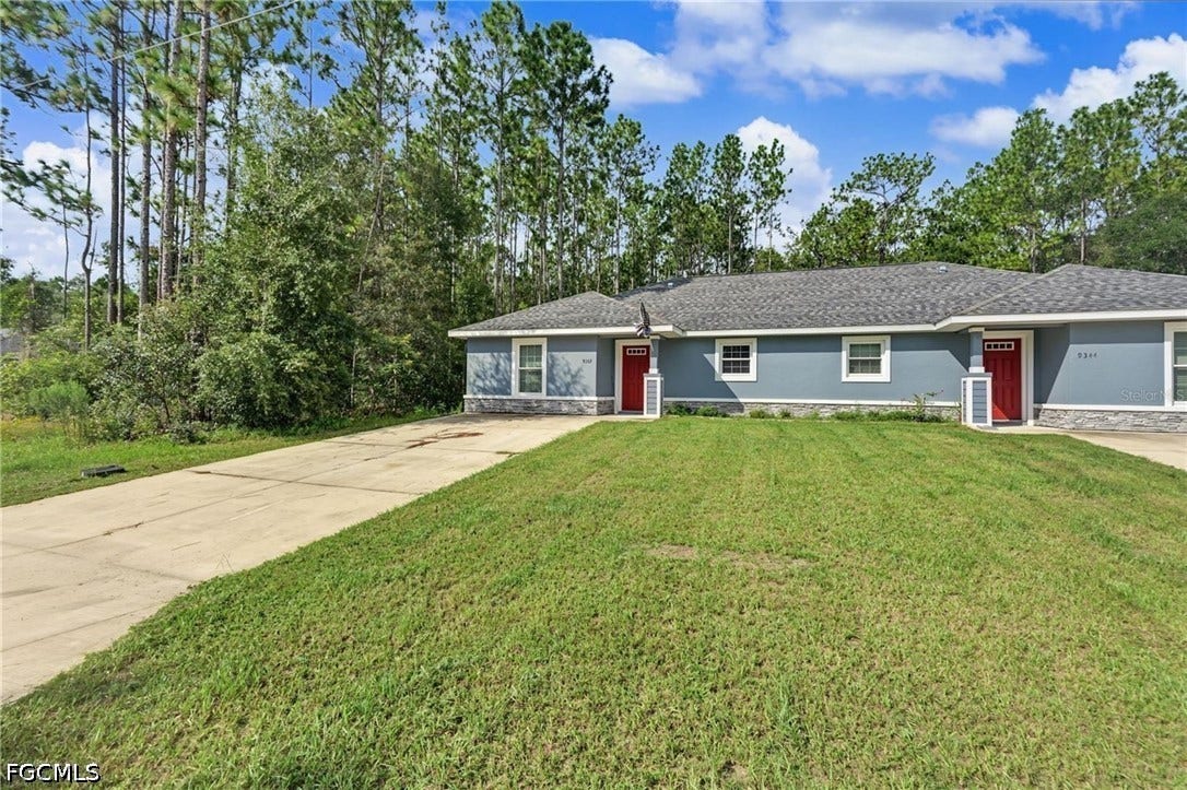 9342/9344 N Peachtree Way, Citrus Springs, FL 34434 Duplex property featuring a grey shingle roof, light blue exterior siding, red entry doors, and a stone-finish foundation