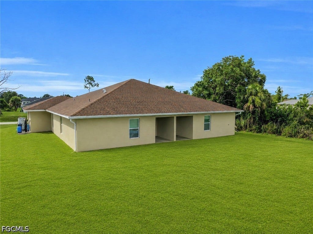 2412/2414 Richard Avenue S, Lehigh Acres, FL 33973 Exterior showcasing a hip roof, stucco siding, multiple windows, and covered outdoor spaces