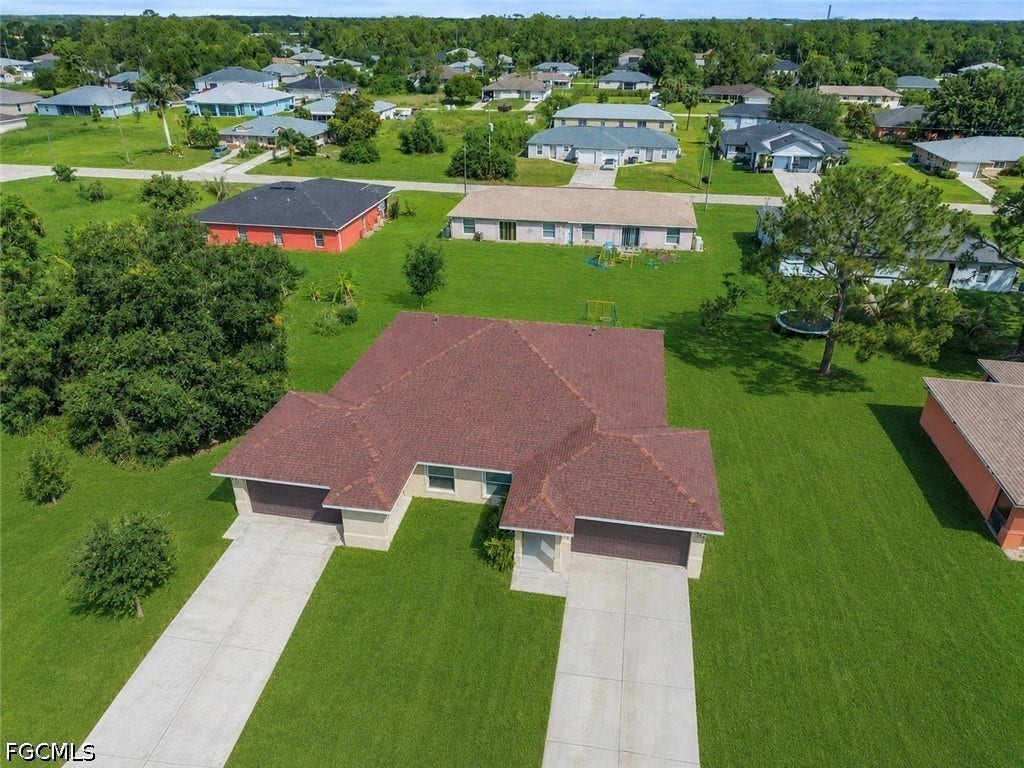 2412/2414 Richard Avenue S, Lehigh Acres, FL 33973 Split-level residential structure featuring a shingled roof, two garage doors, and individual concrete driveways
