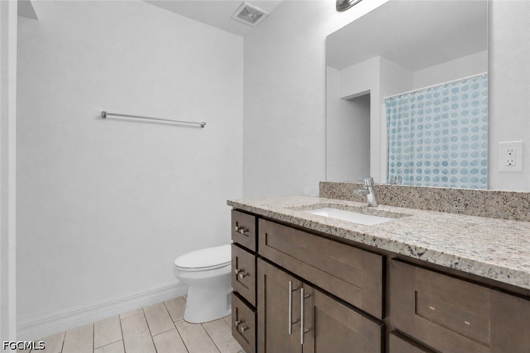 2412/2414 Richard Avenue S, Lehigh Acres, FL 33973 Bathroom vanity with a light-colored granite countertop, undermount sink, and wood-finish cabinetry