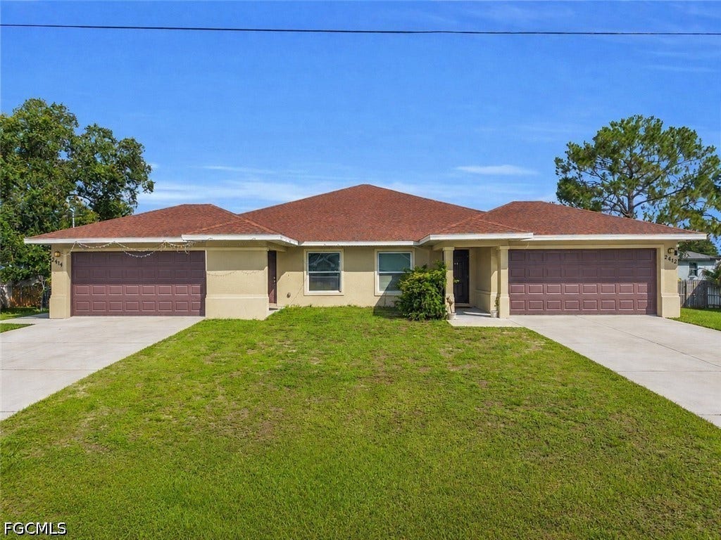2412/2414 Richard Avenue S, Lehigh Acres, FL 33973 Duplex property featuring a neutral stucco exterior, brown garage doors, a red tile roof, and individual concrete driveways
