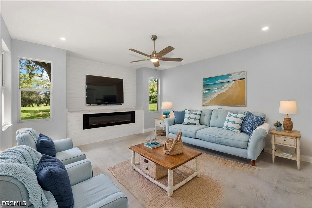 Spacious living area featuring light-toned walls, recessed lighting, and a ceiling fan