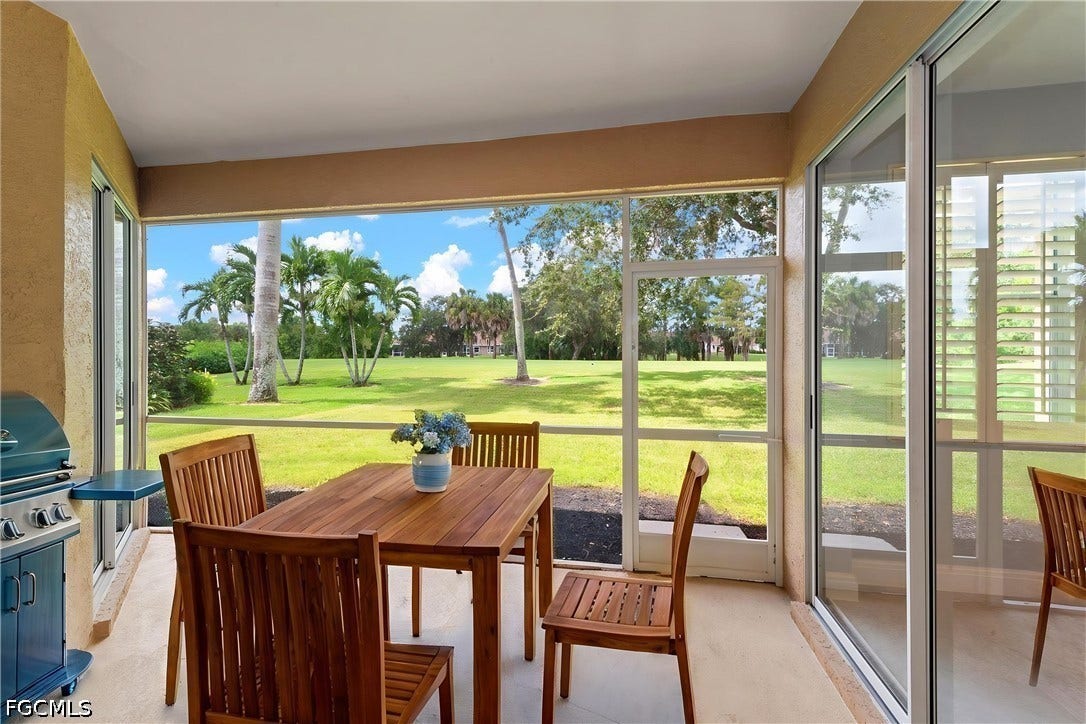 Screened patio with concrete flooring and sliding glass door access, overlooking a manicured lawn and mature palm trees