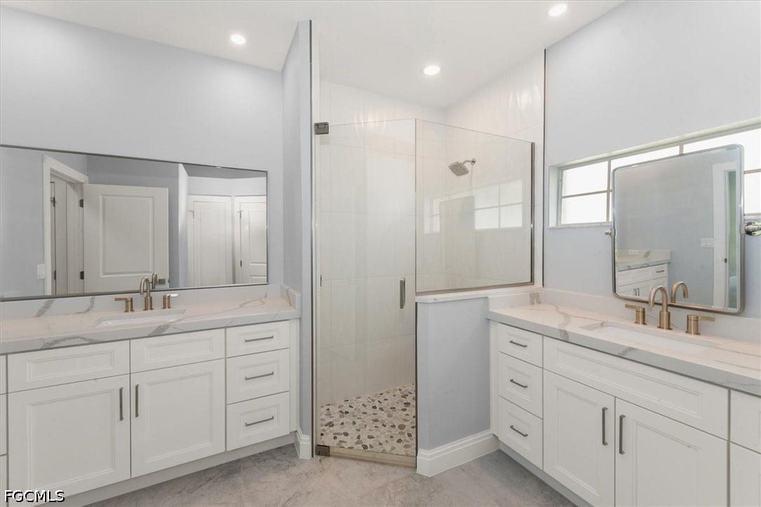 Dual vanities with white cabinetry and stone countertops