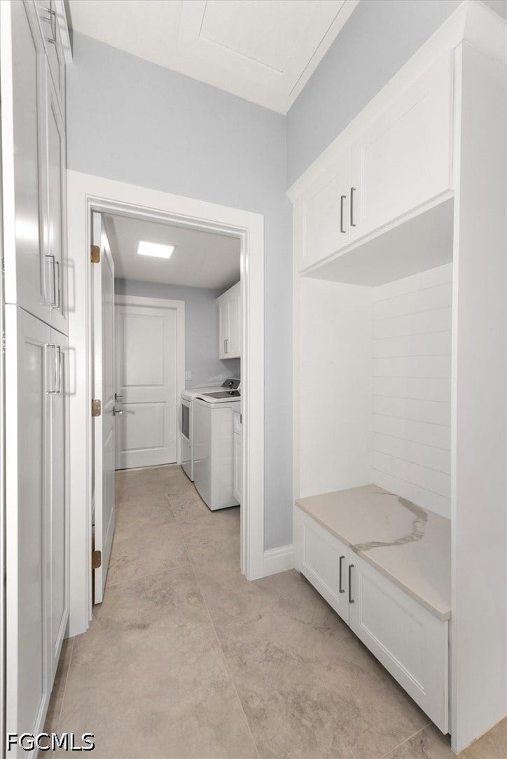 Built-in storage bench with a light-toned countertop, white shaker-style cabinetry, and light-colored floor tiling