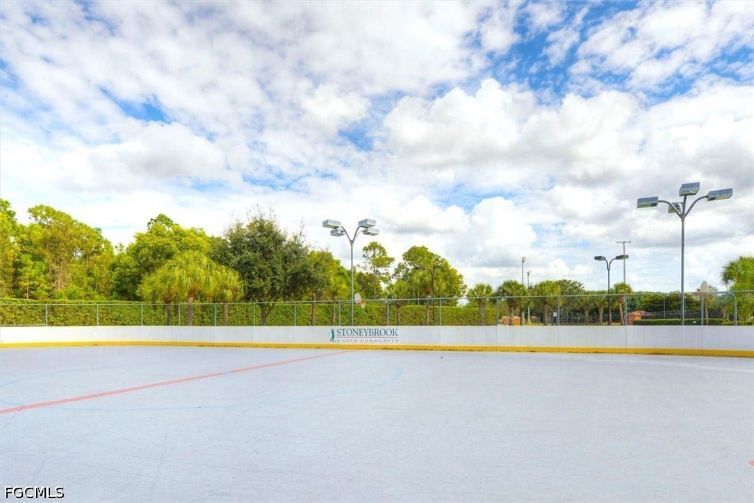 Outdoor court featuring a hard surface, surrounding barrier, and overhead lighting