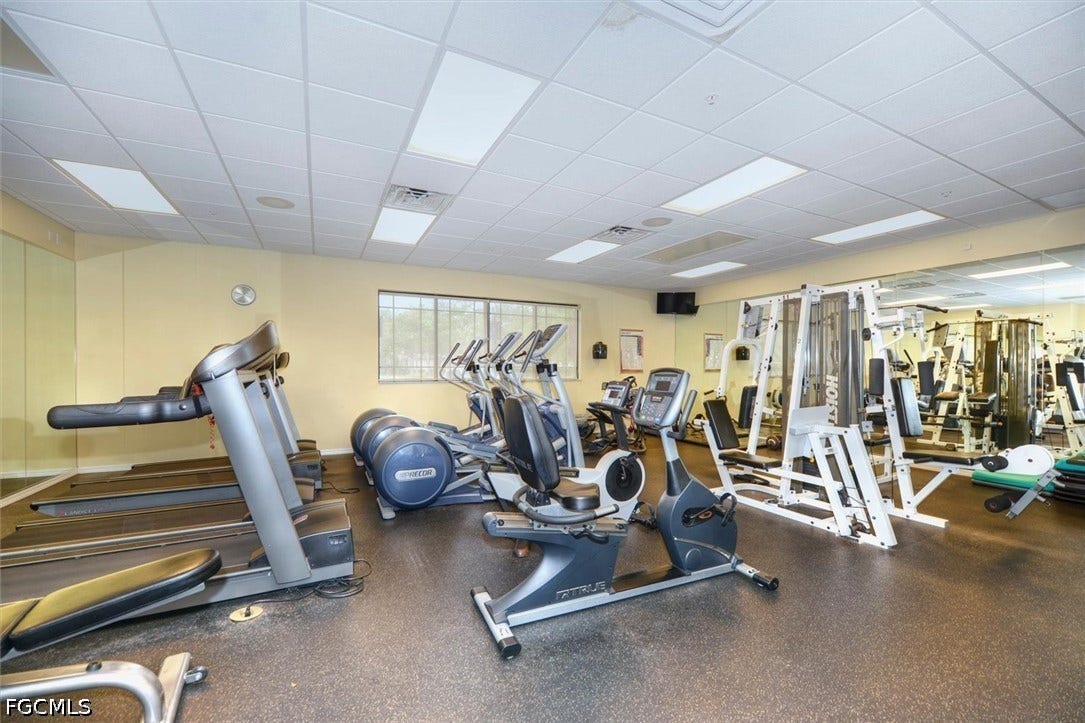 Workout room with rubber flooring, recessed lighting, expansive wall mirrors, and functional windows
