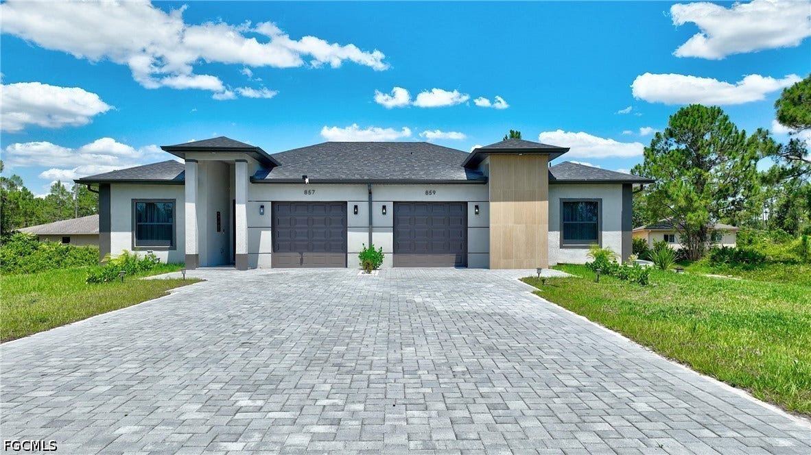 Prairie-style house with stucco siding, a front lawn, a garage, and decorative driveway