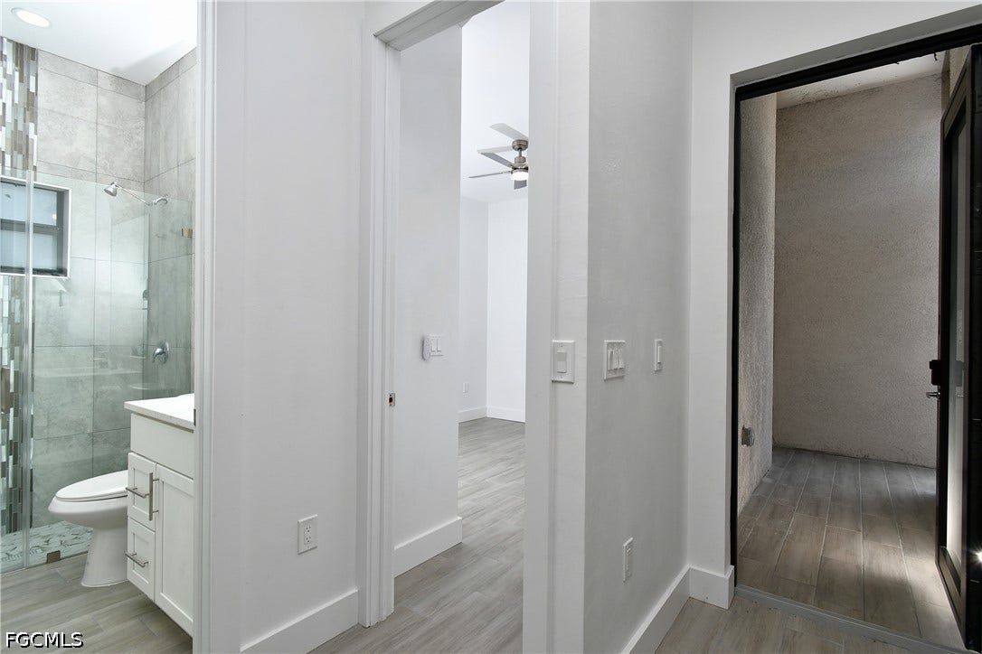 Bathroom with a shower stall, vanity, light wood-type flooring, and a ceiling fan