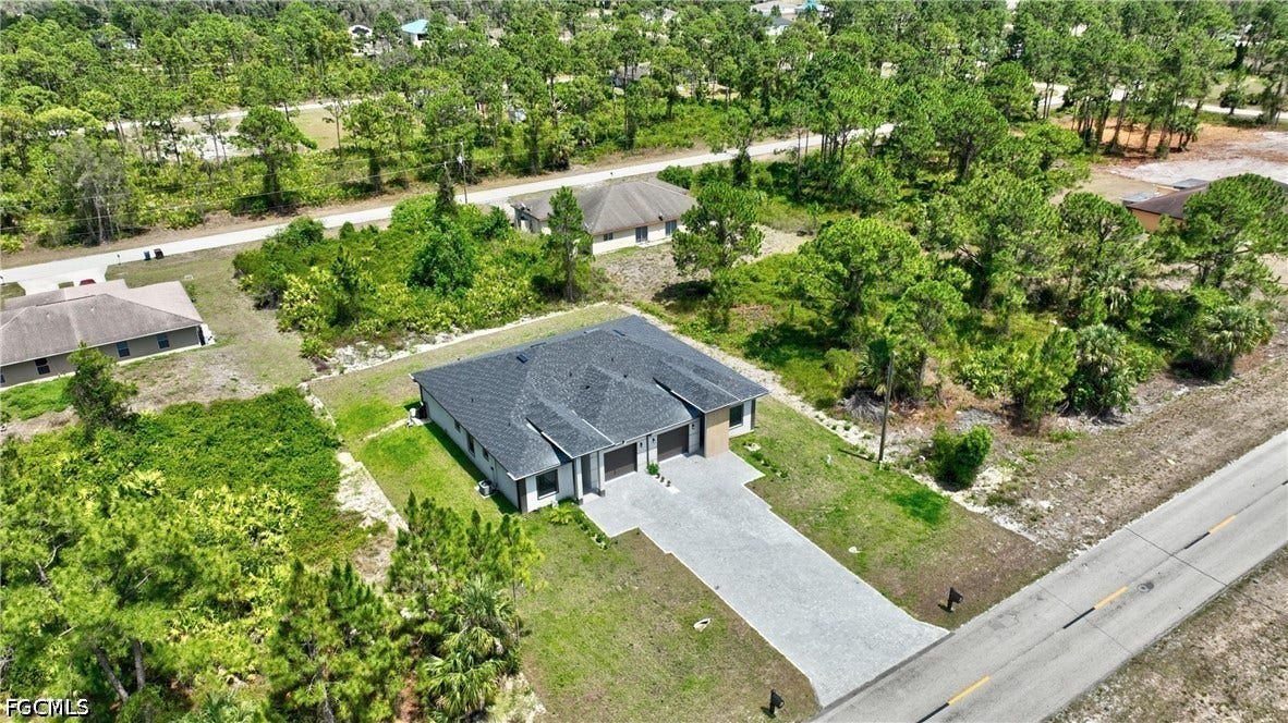 View of subject property featuring a tree filled landscape