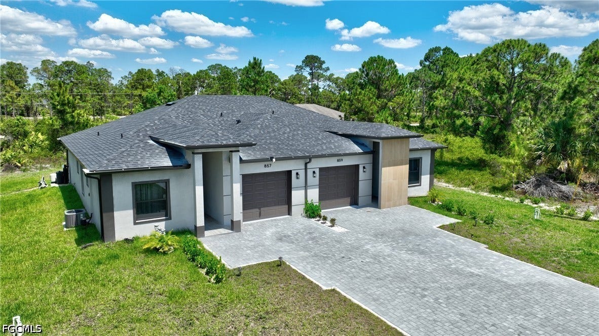 View of front of property featuring a shingled roof, a garage, decorative driveway, and a front lawn