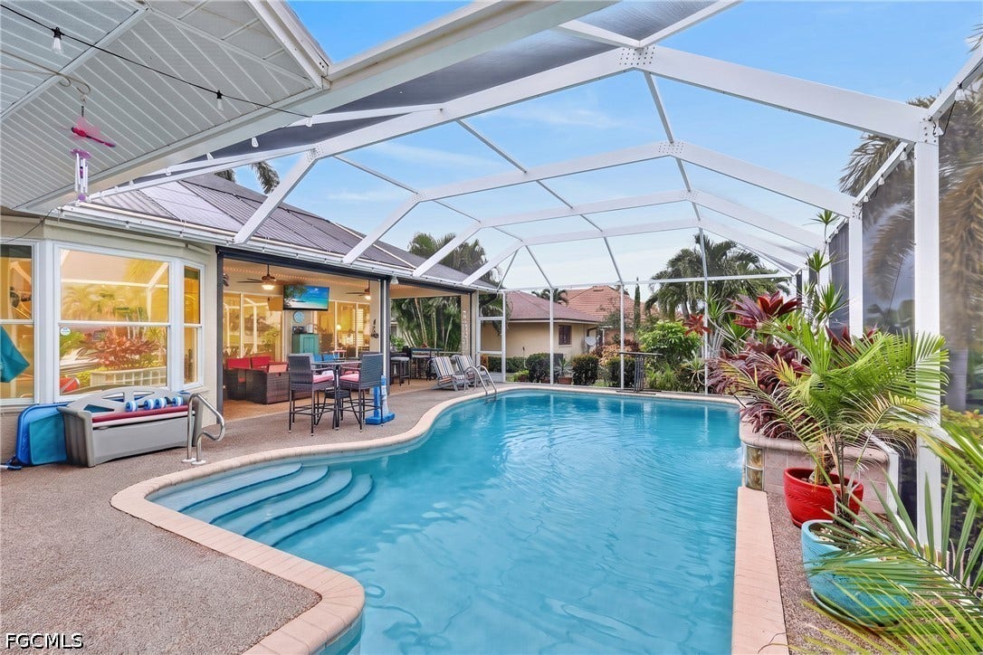 1416 SW 49th Terrace, Cape Coral, FL 33914 Screened lanai with a freeform swimming pool, integrated steps, and a concrete deck