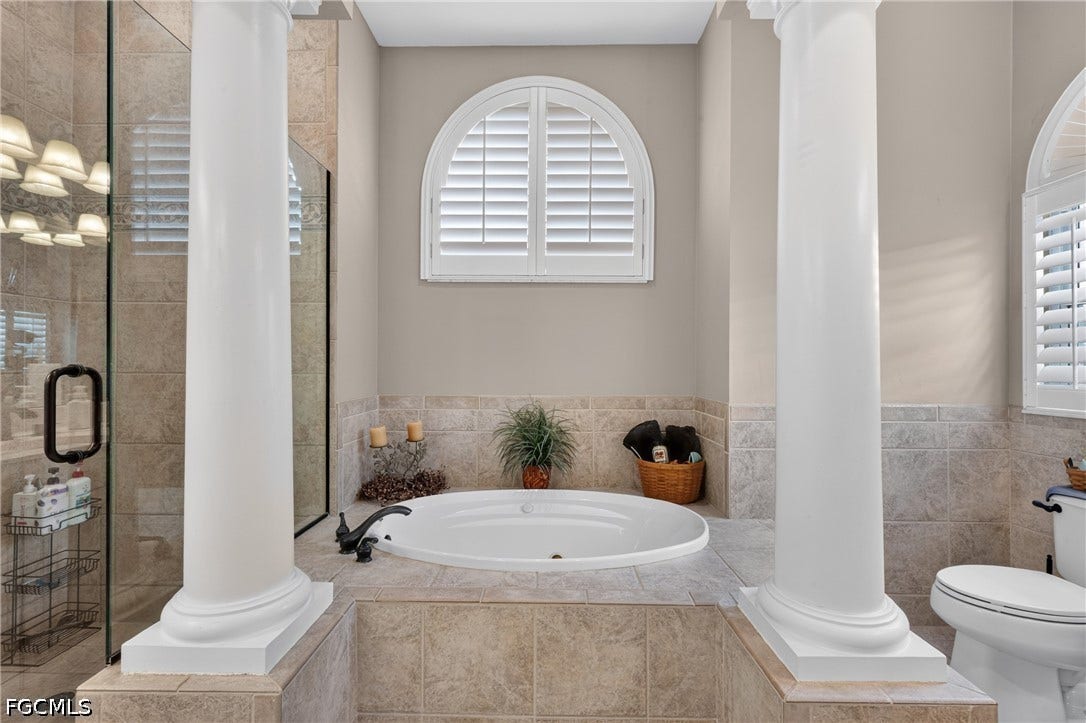 1416 SW 49th Terrace, Cape Coral, FL 33914 Soak tub - built-in bathtub with a dark bronze faucet, arched window featuring white plantation shutters, glass-enclosed shower with dark bronze hardware, and light-toned tile flooring