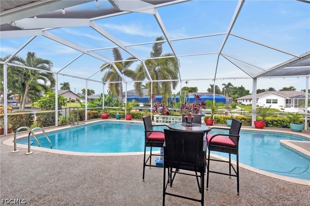 1416 SW 49th Terrace, Cape Coral, FL 33914 Screened lanai with a freeform pool, integrated spa, and textured concrete decking