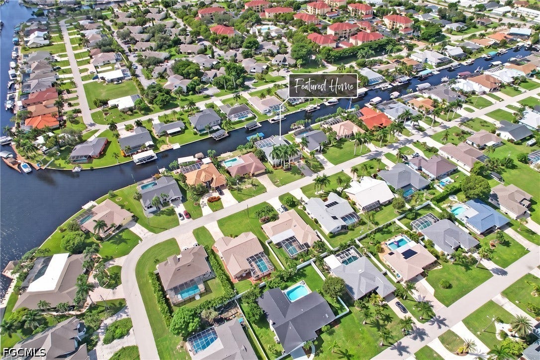 1416 SW 49th Terrace, Cape Coral, FL 33914 Waterfront property with direct canal access, featuring a private boat dock and a screened lanai with an in-ground pool