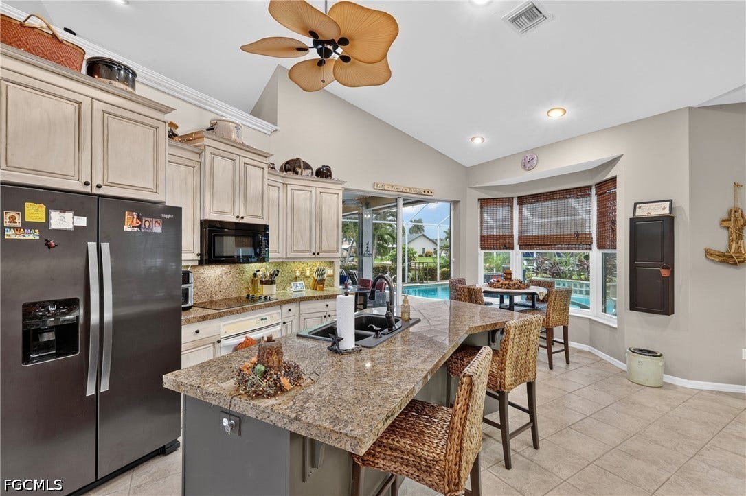 1416 SW 49th Terrace, Cape Coral, FL 33914 Vaulted ceilings, a kitchen island with seating, a bay window with a dining area, tile flooring, and direct access to a screened patio and pool