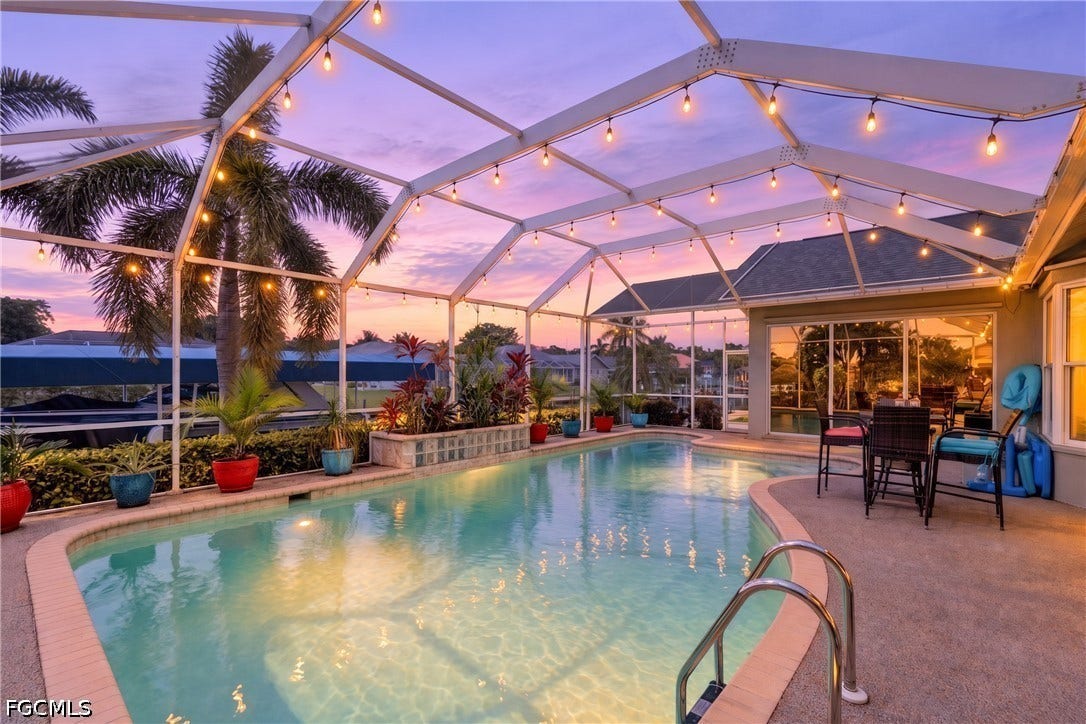1416 SW 49th Terrace, Cape Coral, FL 33914 Screened-in swimming pool with a curved edge, surrounding paved patio, and integrated planters