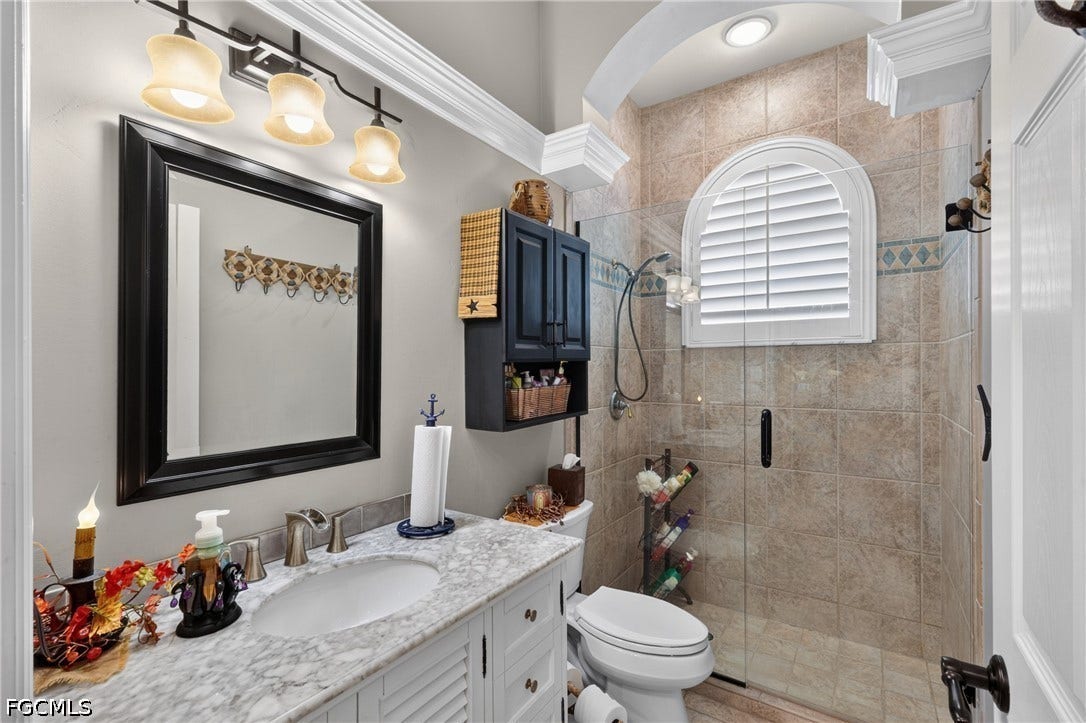 1416 SW 49th Terrace, Cape Coral, FL 33914 Guest bath with walk in shower - Vanity with an undermount sink, marble-finish countertop, and decorative mirror