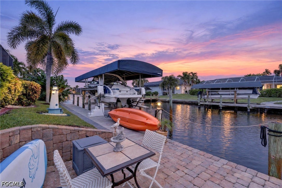 1416 SW 49th Terrace, Cape Coral, FL 33914 Waterfront setting with a boat lift, paved patio, and mature palm trees