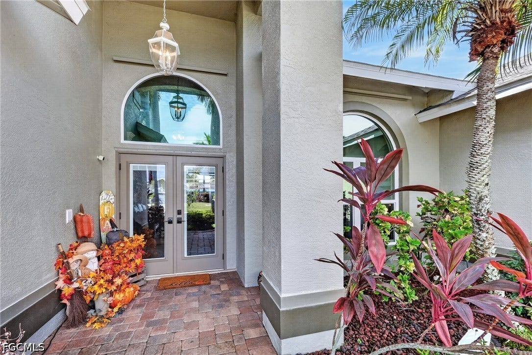 1416 SW 49th Terrace, Cape Coral, FL 33914 Double-door entry with arched transom window, brick paver flooring, and exterior wall sconce