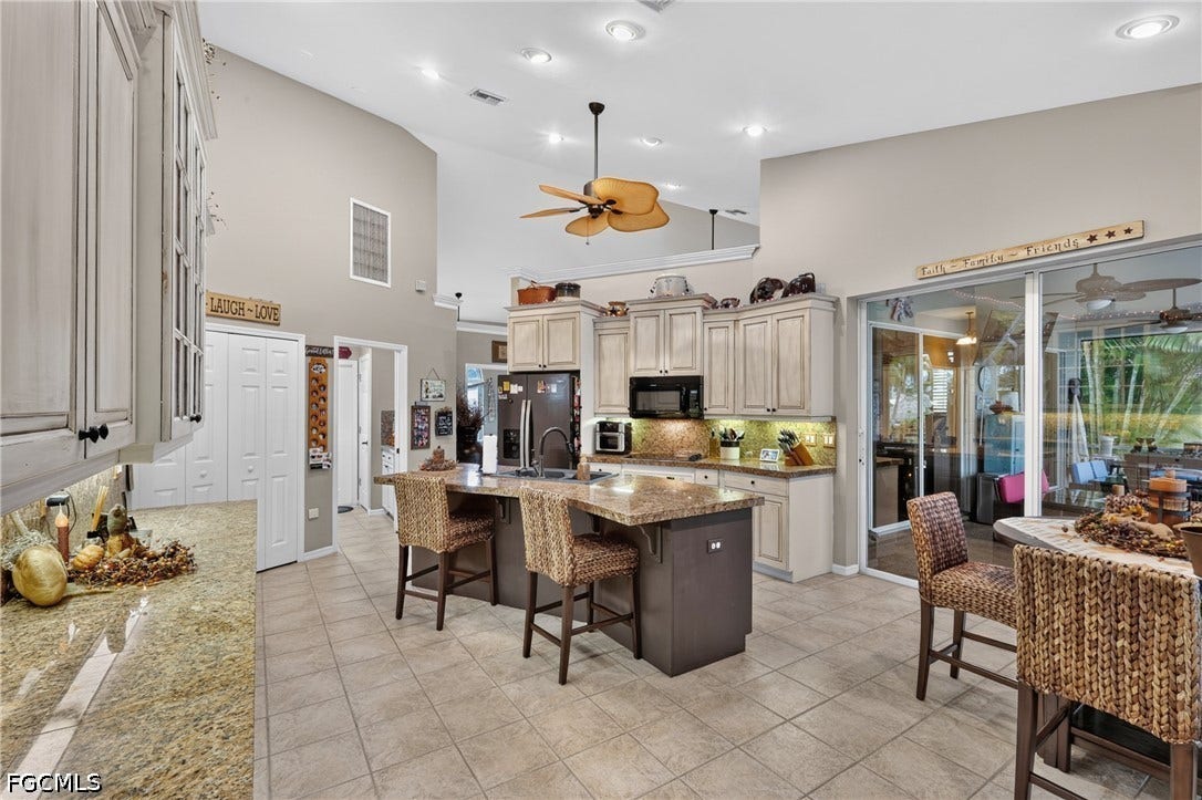 1416 SW 49th Terrace, Cape Coral, FL 33914 Vaulted ceilings, recessed lighting, and a kitchen island with built-in seating complement the light-toned cabinetry and tile flooring