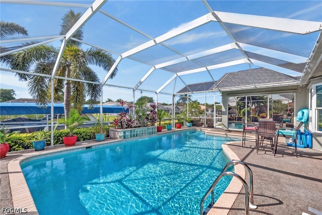 1416 SW 49th Terrace, Cape Coral, FL 33914 Screened pool enclosure featuring a large swimming pool with integrated steps and a pool deck