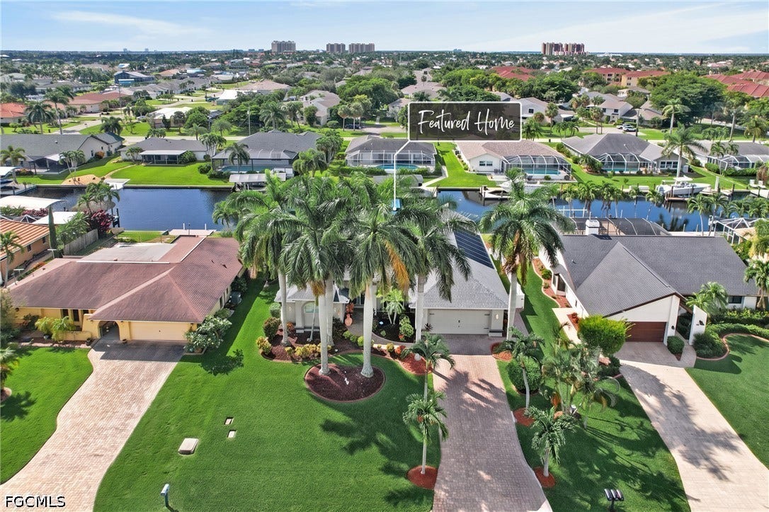 1416 SW 49th Terrace, Cape Coral, FL 33914 Waterfront property with canal access, mature palm trees, manicured lawns, and paved driveways