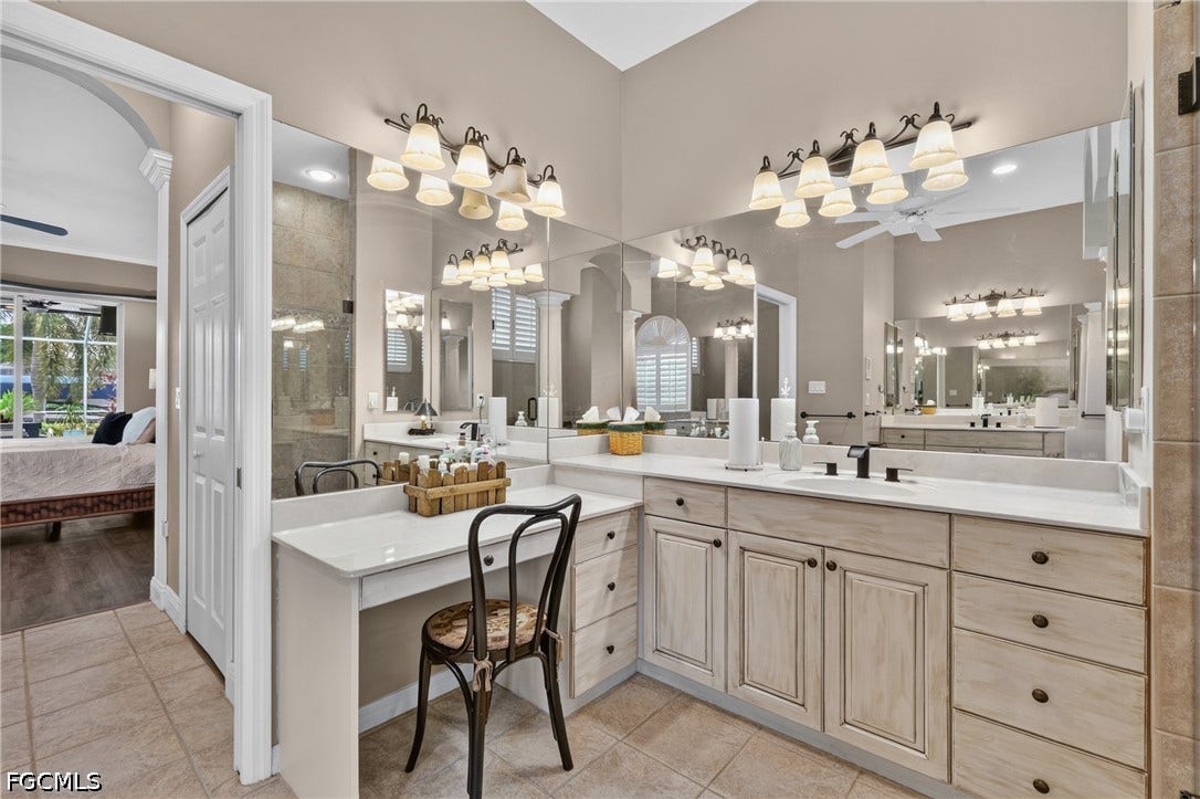 1416 SW 49th Terrace, Cape Coral, FL 33914 Double vanity with integrated sinks, white countertops, extensive mirror coverage, and built-in vanity desk