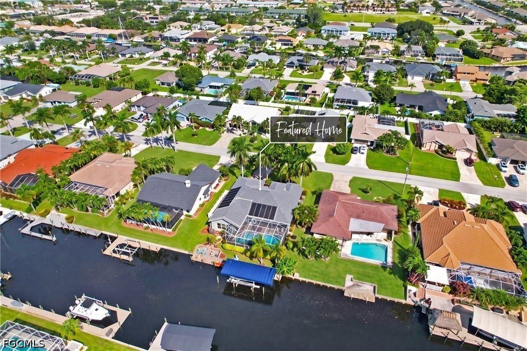 1416 SW 49th Terrace, Cape Coral, FL 33914 Waterfront property featuring a private boat dock, screened-in swimming pool, and solar panels