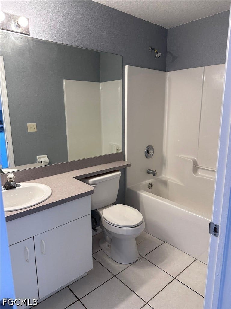 2926 SE Santa Barbara Place, Cape Coral, FL 33904 White tiled flooring, vanity with integrated sink, toilet, and a combined shower and bathtub unit