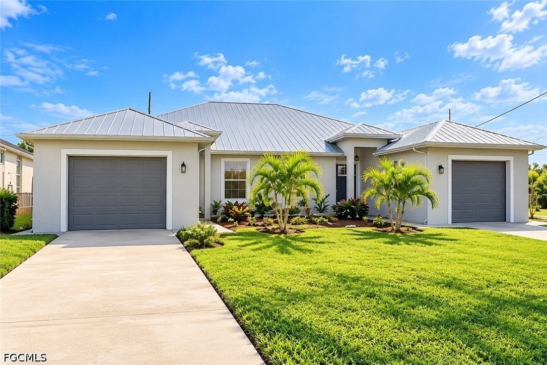 2926 SE Santa Barbara Place, Cape Coral, FL 33904 Contemporary stucco exterior with a metal roof, dual garage doors, concrete driveway, and established landscaping