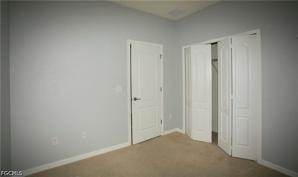 14495 Vindel Circle, Fort Myers, FL 33905 Neutral wall paint, carpet flooring, white interior door, and bi-fold closet doors with interior shelving