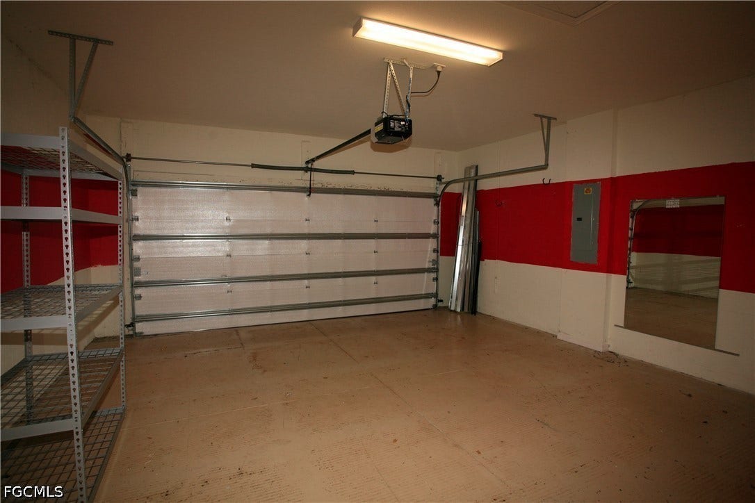 14495 Vindel Circle, Fort Myers, FL 33905 Garage featuring a single overhead door, an automatic garage door opener, fluorescent lighting, and built-in metal shelving