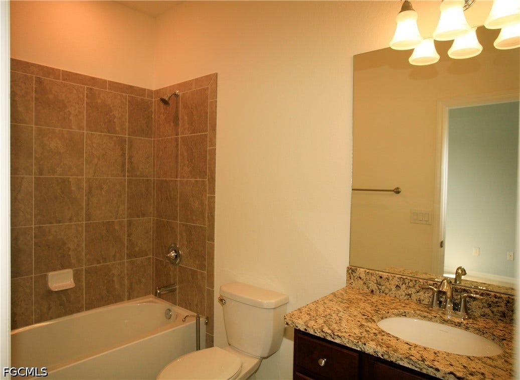 14495 Vindel Circle, Fort Myers, FL 33905 Built-in bathtub with subway tile surround, vanity with granite countertop, integrated sink, and chrome fixtures
