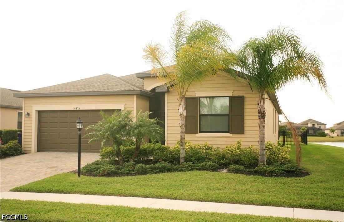 14495 Vindel Circle, Fort Myers, FL 33905 Tan siding exterior with a brown garage door, paver driveway, and a shingle roof