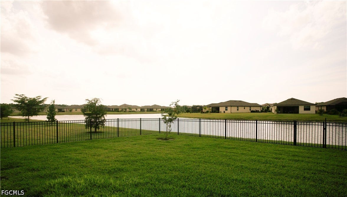 14495 Vindel Circle, Fort Myers, FL 33905 Expansive green lawn with a black metal fence bordering a body of water