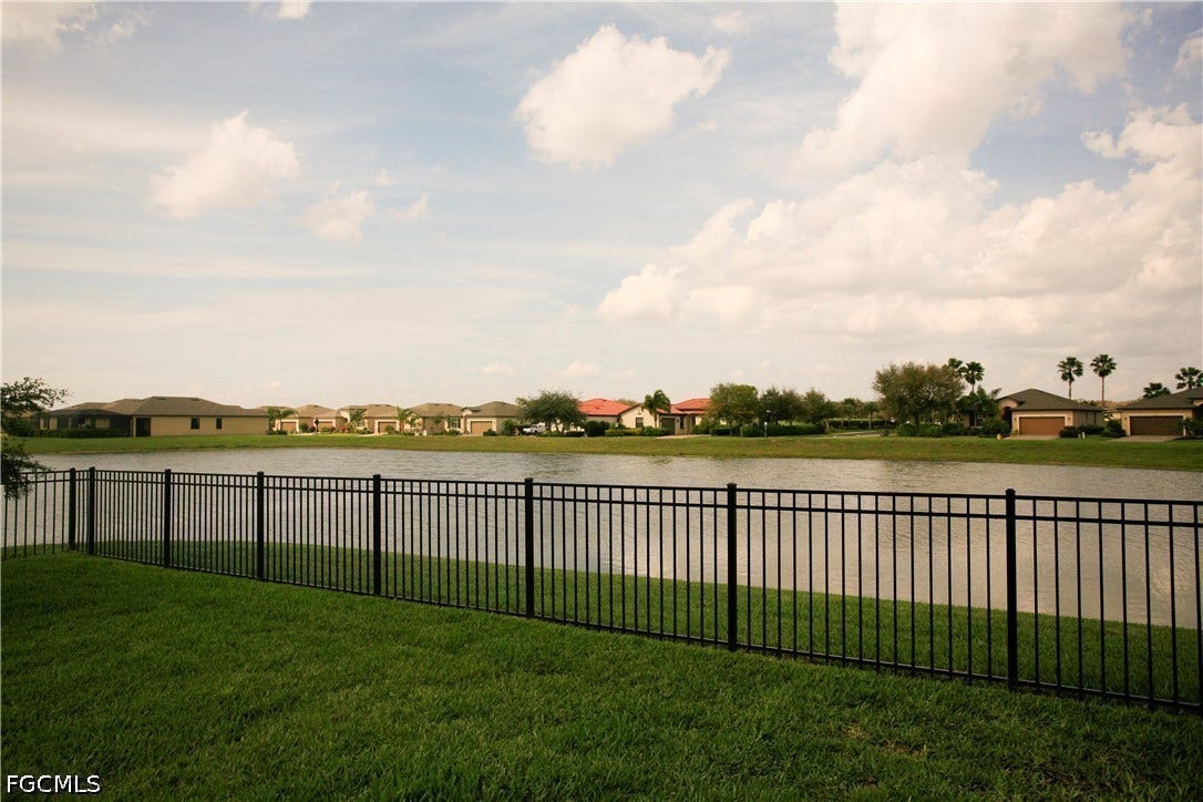 14495 Vindel Circle, Fort Myers, FL 33905 Expansive lawn with a black metal fence bordering a water feature