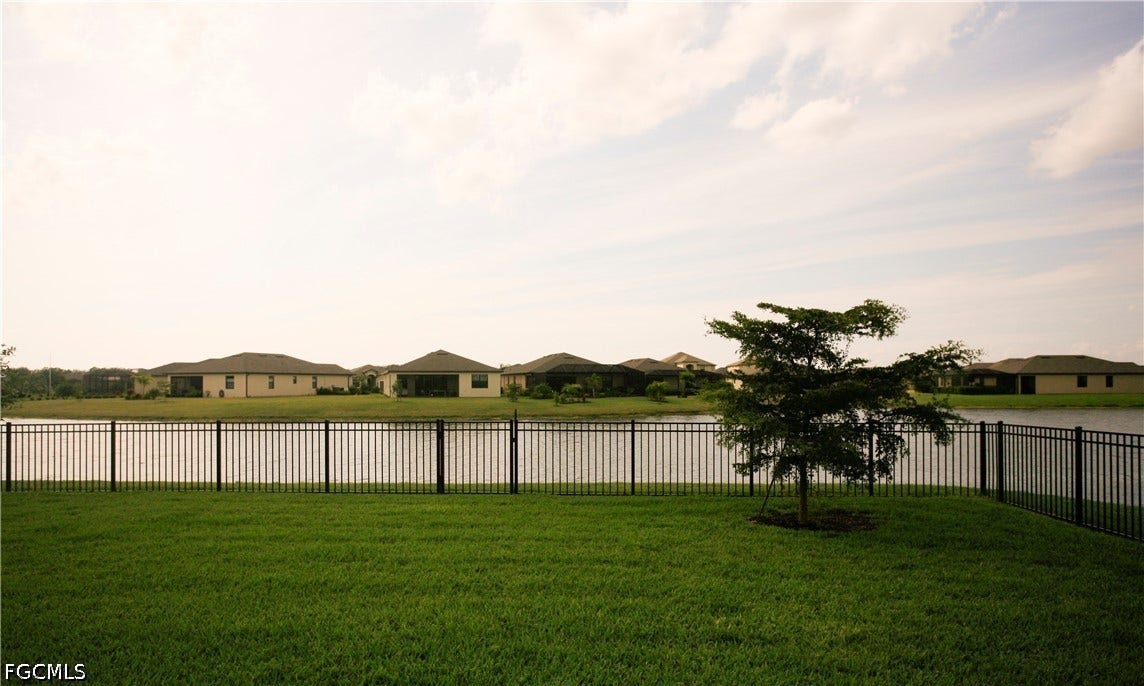 14495 Vindel Circle, Fort Myers, FL 33905 Manicured lawn with a young tree, bordered by a black metal fence