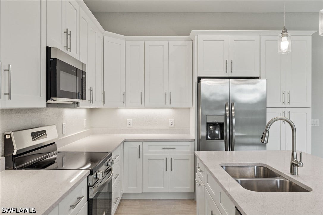 4713 6th Street W, Lehigh Acres, FL 33971 Gourmet kitchen with quartz island, shaker cabinets, and premium luxury vinyl plank (LVP) flooring upgrade.